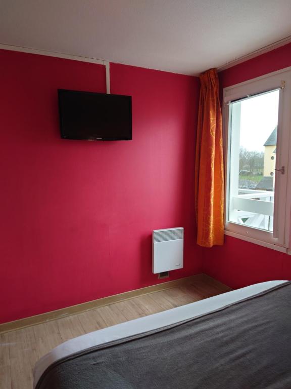 a bedroom with a red wall with a tv on the wall at Fasthotel Angers Beaucouzé in Beaucouzé