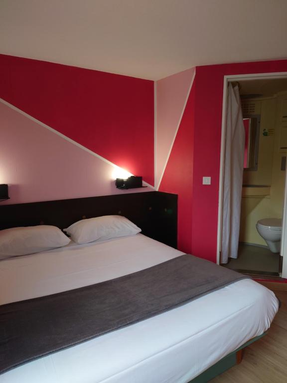 a bedroom with a bed with a red wall at Fasthotel Angers Beaucouzé in Beaucouzé