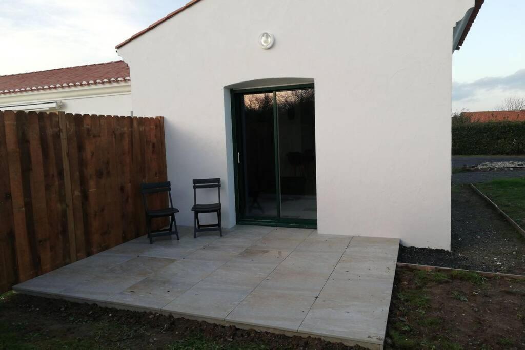 eine Terrasse mit zwei Stühlen neben einem weißen Haus in der Unterkunft Appart du peuble, lumineux in Brétignolles-sur-Mer