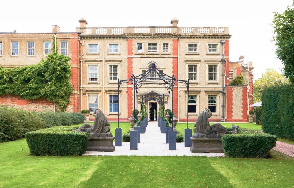 un bâtiment avec deux statues devant lui dans l'établissement The Elms Hotel & Spa, à Abberley