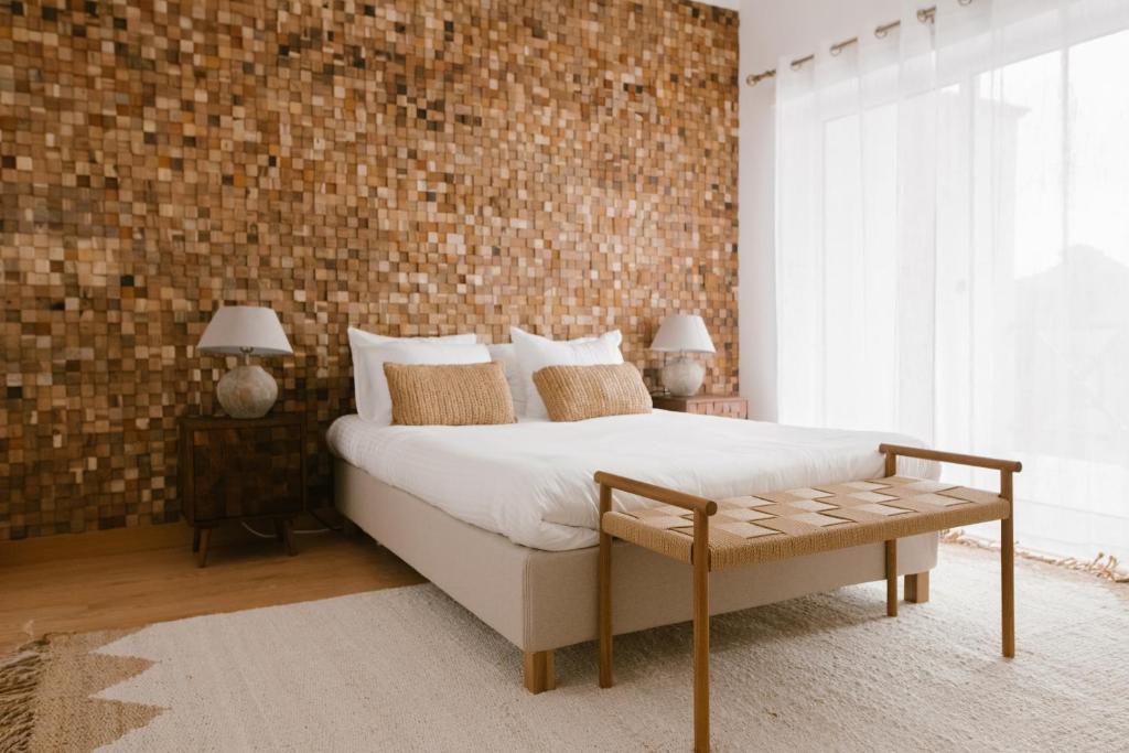 ein Schlafzimmer mit einem Bett und einer Ziegelwand in der Unterkunft Casa amigavel da Terra in Sesimbra