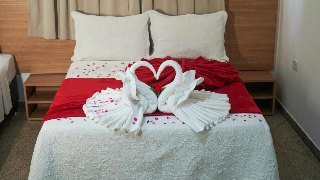 Una cama con dos cisnes hechos para parecer corazones en Maragogi Suítes, en Maragogi