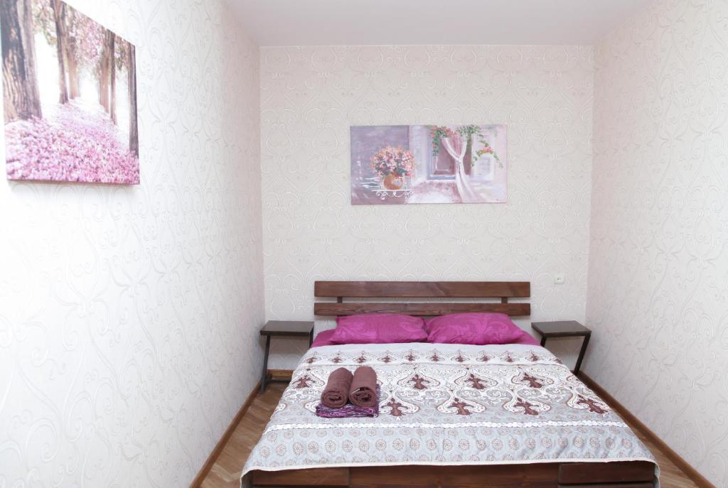 a bedroom with a bed with pink pillows and shoes at Apartments on Yavornitsky av. in Dnipro