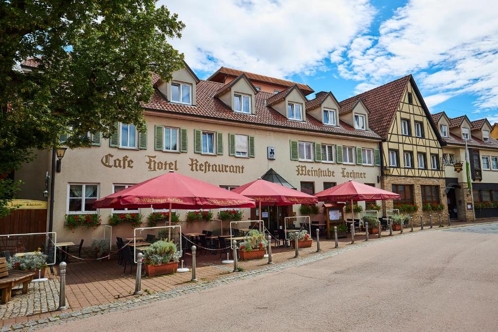 un edificio con mesas y sombrillas rojas en una calle en Flair Hotel Weinstube Lochner en Bad Mergentheim