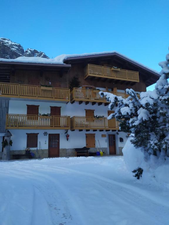 a building with snow on the ground in front of it at Residence Marmolada in Rocca Pietore