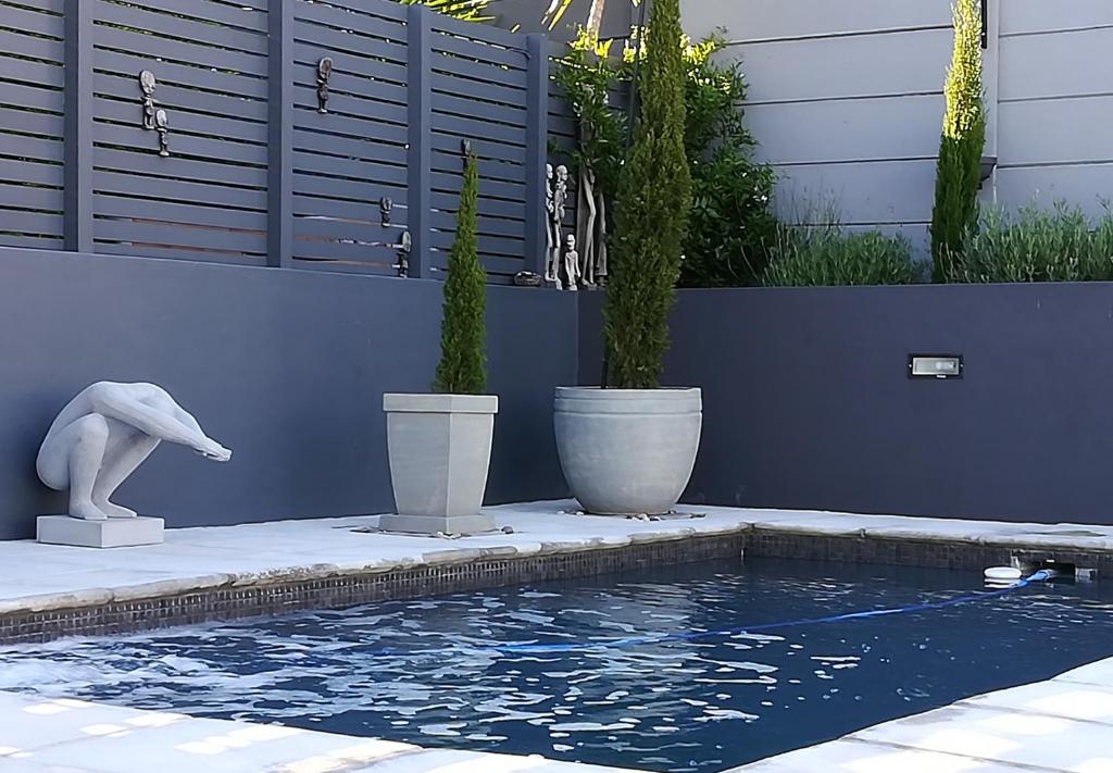 una piscina con due piante in vaso accanto a una casa di One Above a Città del Capo