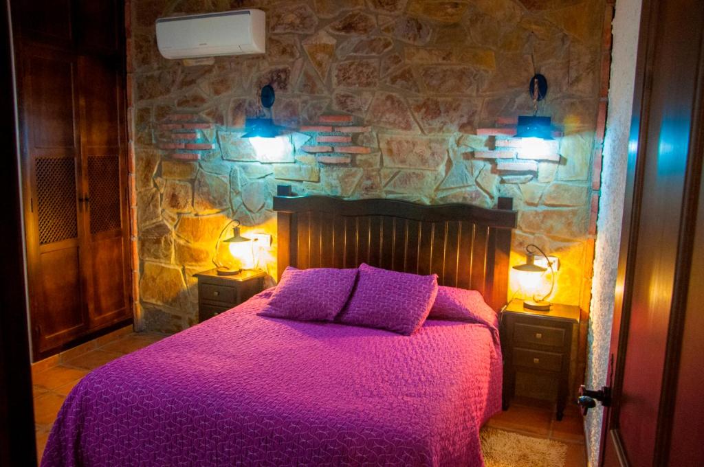 1 dormitorio con 1 cama con sábanas moradas y 2 luces en Apartamentos Rurales Tierras de Granadilla, en Zarza de Granadilla