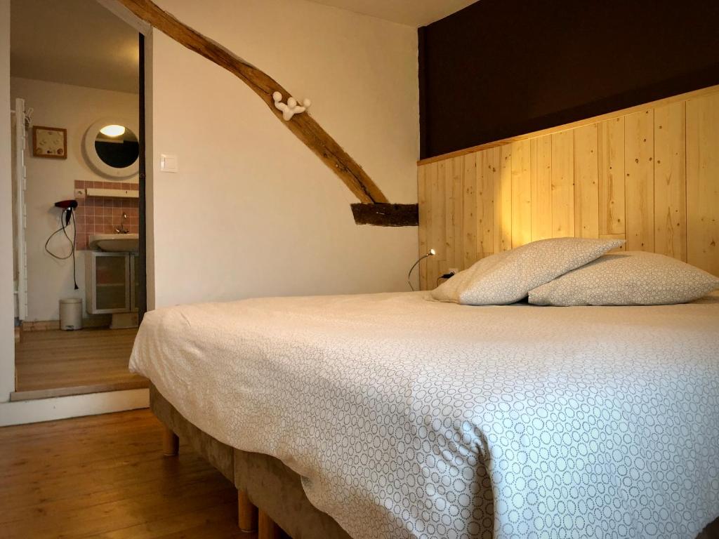 um quarto com uma cama grande e uma cabeceira em madeira em "Le petit Moulinsard" em Bernay
