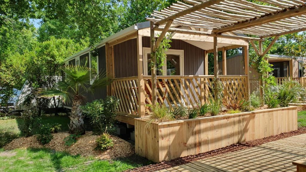 a tiny house with a pergola in a yard at Camping Aux Couleurs du ferret in Lège-Cap-Ferret