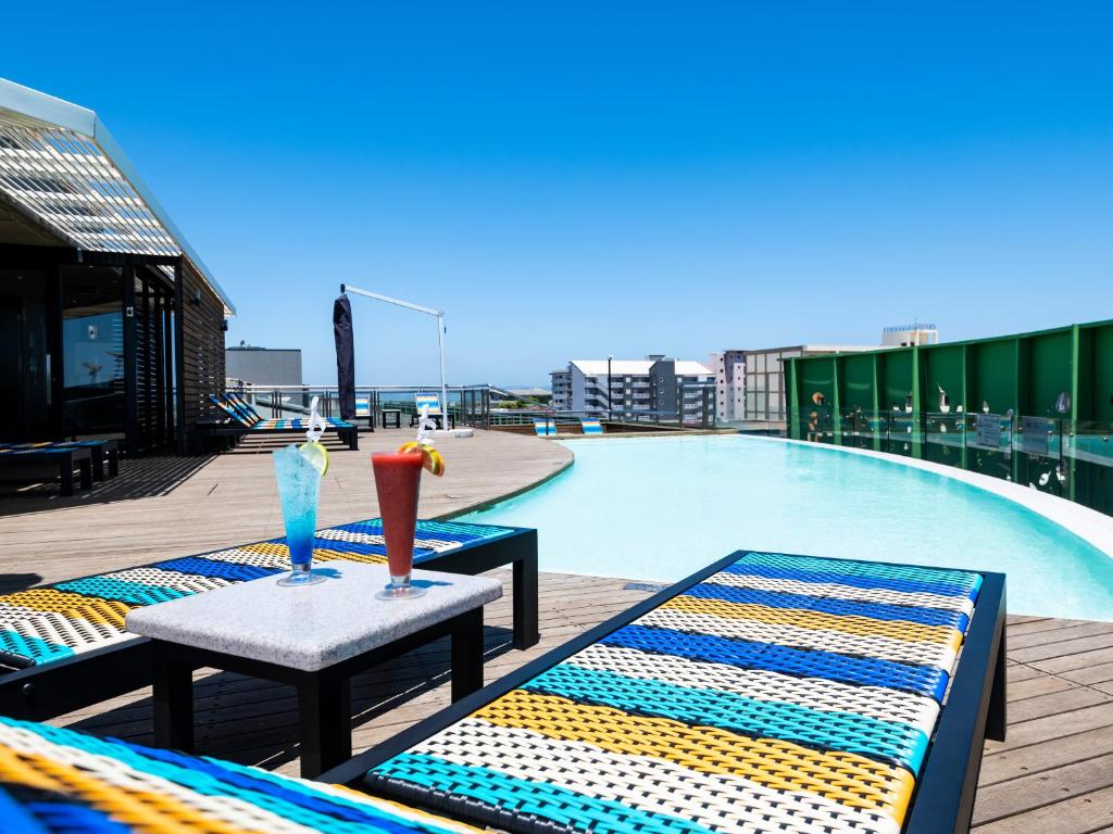 twee stoelen en een tafel naast een zwembad bij aha Gateway Hotel Umhlanga in Durban