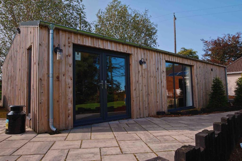 ein Holzgebäude mit einer großen Glastür in der Unterkunft The Cabin - Luxury Country Living in Cullybackey