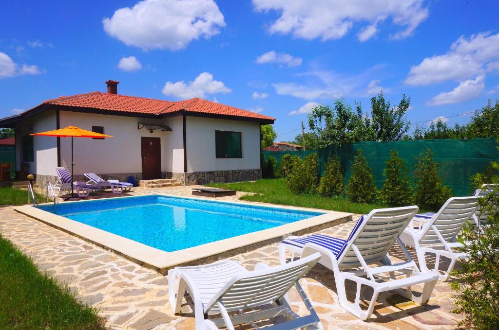 a swimming pool with white chairs and a house at Вила Едем - Villa Edem - Beach Bolata Area in Bŭlgarevo