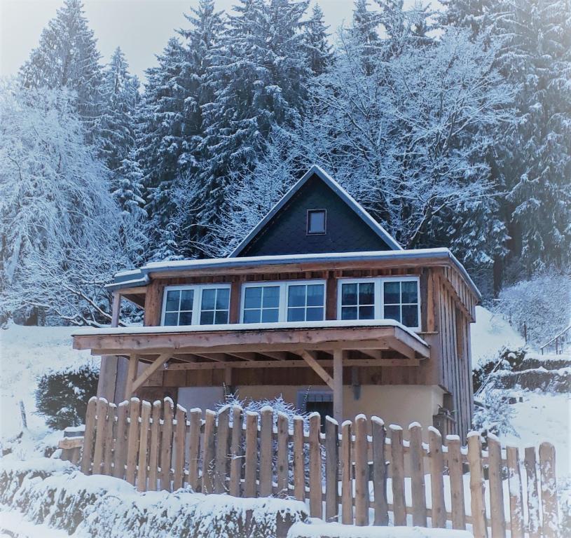 ein Haus mit einem Zaun im Schnee in der Unterkunft Mäcky Baude in Dippoldiswalde