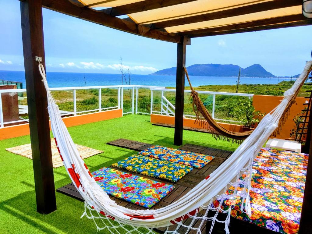 a hammock on a balcony with a view of the ocean at Areias do Sol Suítes in Florianópolis