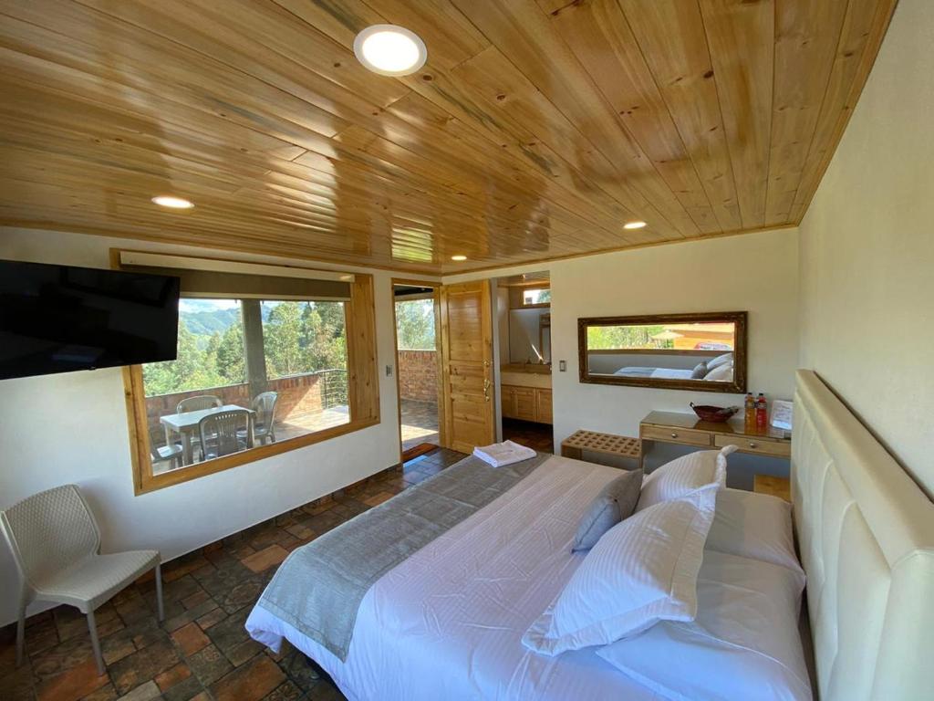 a bedroom with a large bed and a tv in it at Romántica Cabaña con vista a la ciudad, 10 min del Centro in Chiquinquirá
