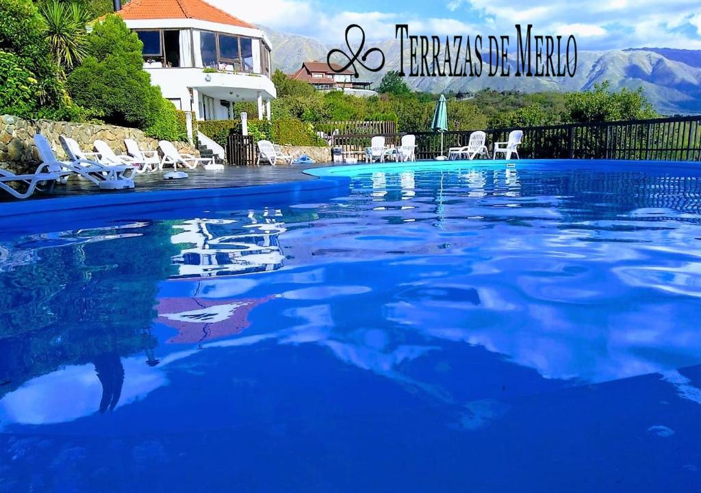 a large swimming pool with chairs and a house at Terrazas de Merlo Aparts con servicios in Merlo