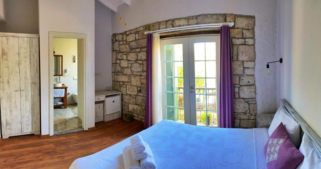 a bedroom with a bed and a stone wall at Oberj d'Azur Alaçatı in Alaçatı