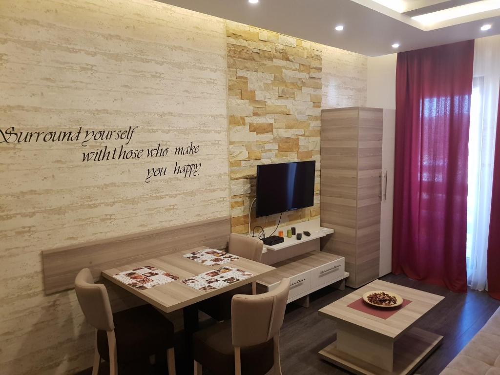 ein Wohnzimmer mit einem Tisch und einem TV in der Unterkunft Apartman K5 Milmari Resort in Kopaonik