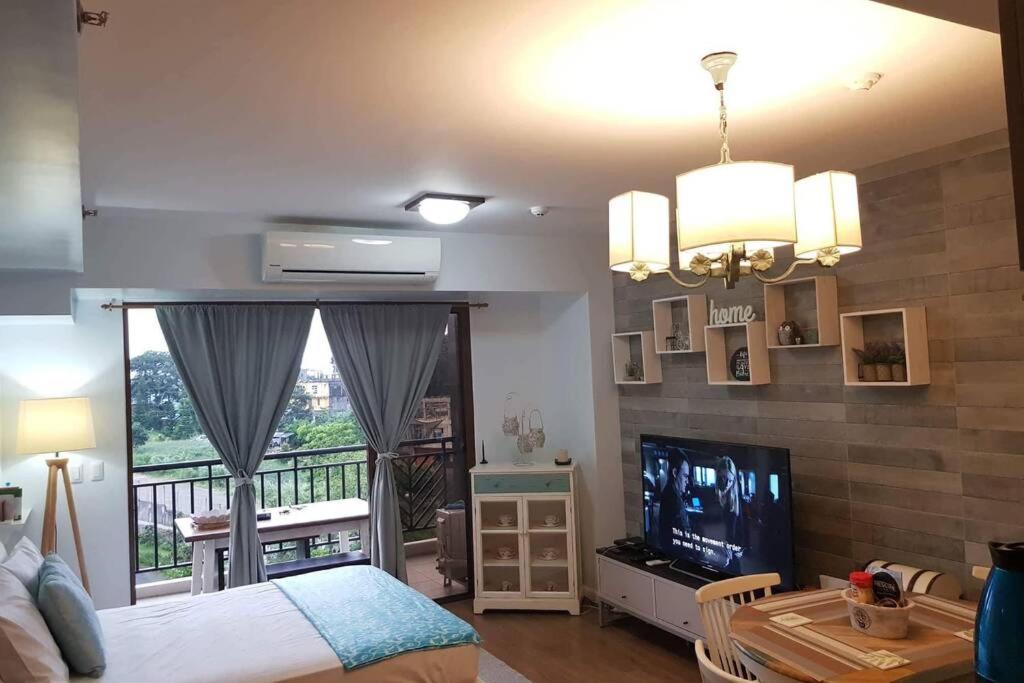 a bedroom with a bed and a television and a balcony at BIiss at Kasa Luntian with WIFI, Netflix and Nature s View in Tagaytay