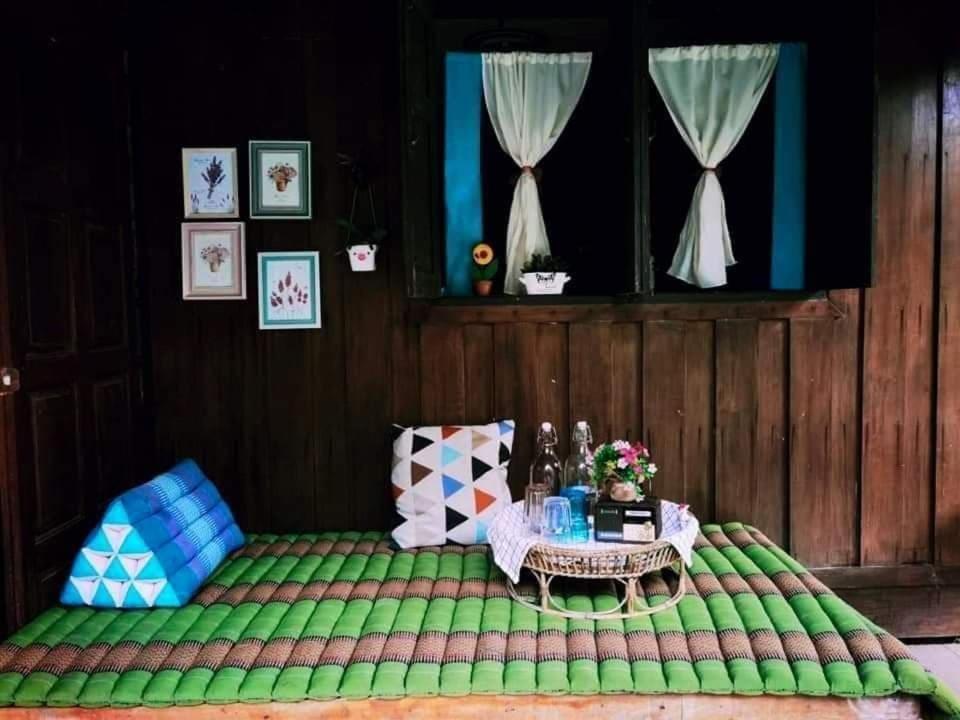 Habitación con cama verde y mesa. en Nakhon Si Ban Na Homestay en Nakhon Si Thammarat