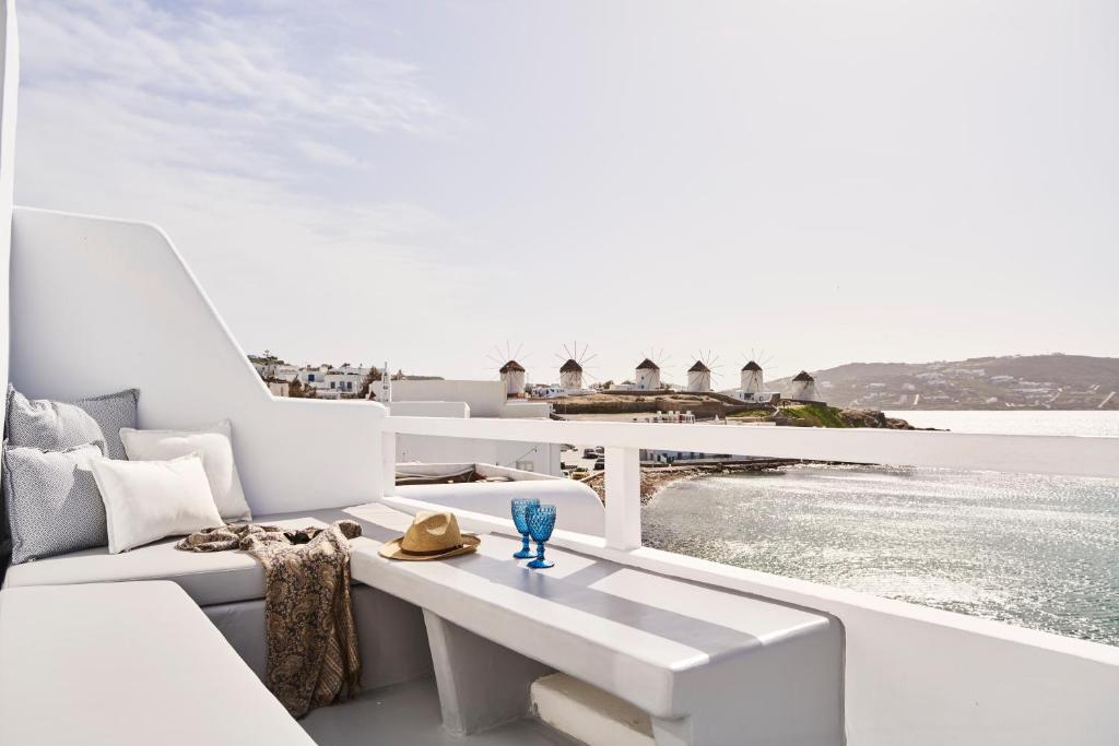 einen Balkon mit weißen Möbeln und Blick auf das Wasser in der Unterkunft Little Venice Suites in Mykonos Stadt