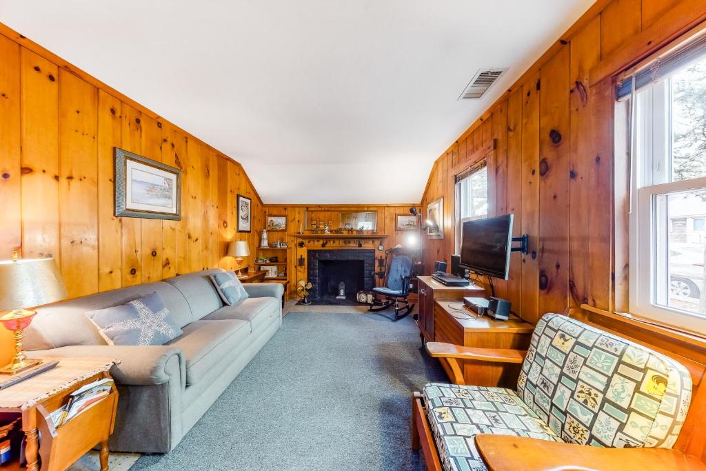 a living room with a couch and a tv at Uncle Rolfs Cozy Cottage in Dennis Port