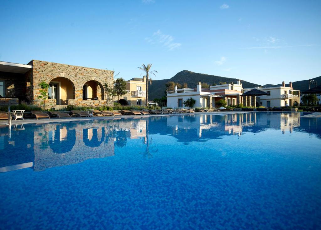 a large pool of blue water in a resort at Porto Kea Suites in Korissia