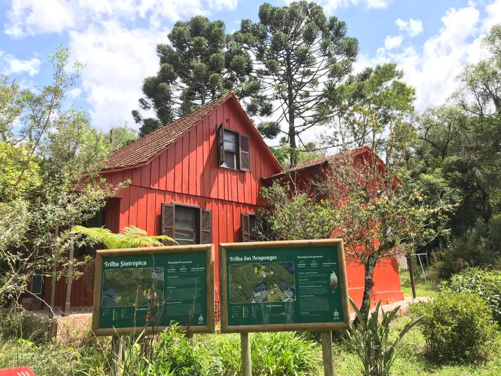 ein rotes Haus mit einem Schild davor in der Unterkunft Casa Colonial Santuário Bellatrix in Faxinal dos Castilhos