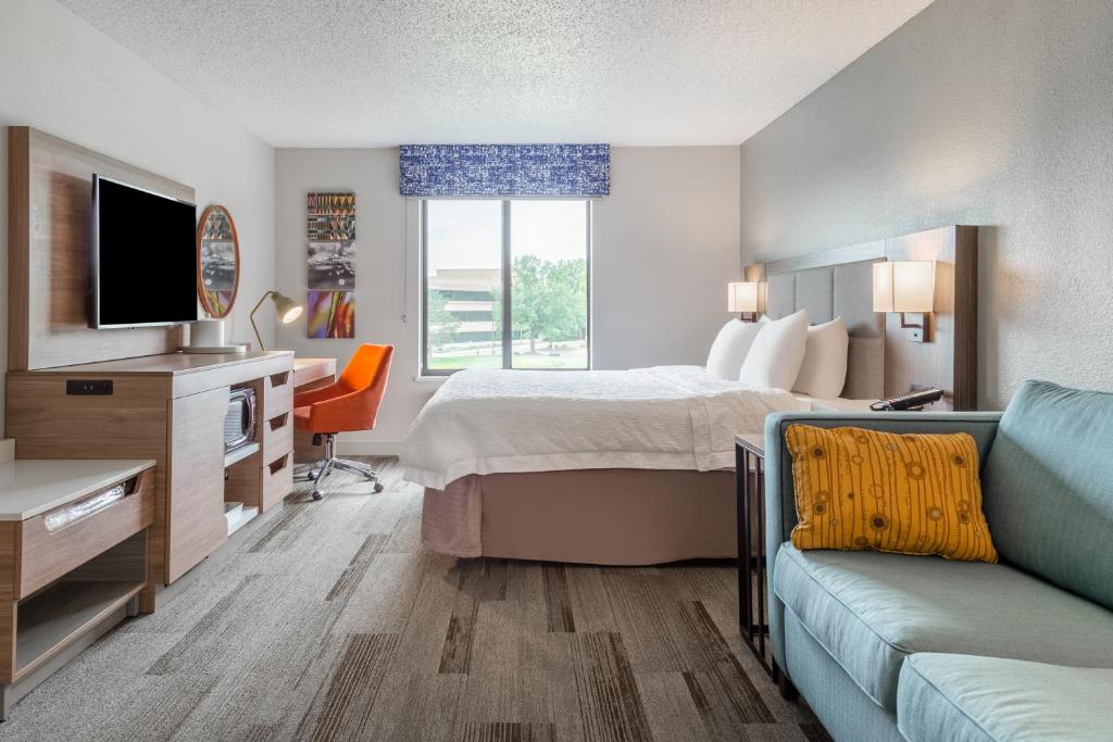Hampton Inn La Crosse/Onalaska في Onalaska: غرفة في الفندق بها سرير وتلفزيون وأريكة