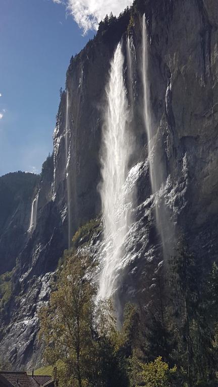 einem Wasserfall an der Seite eines Berges in der Unterkunft Hornerpub Apartments in Lauterbrunnen