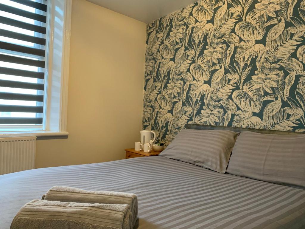 1 dormitorio con 1 cama y papel pintado con motivos florales en Malibu Hotel, en Blackpool