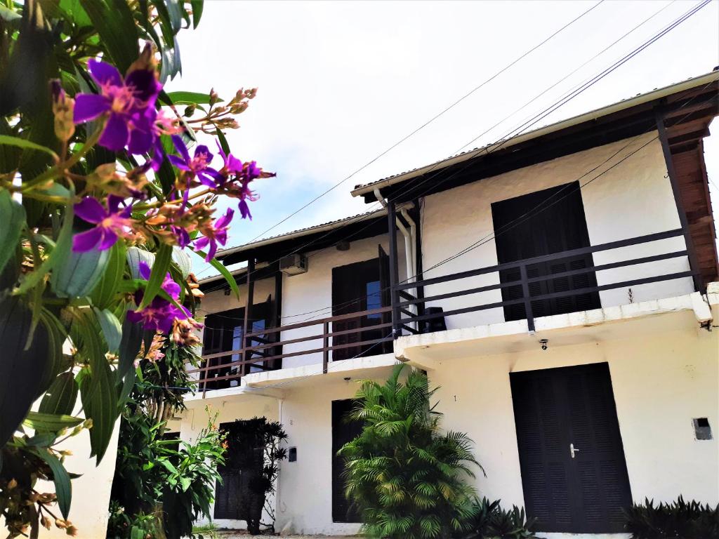 - un bâtiment blanc avec des fenêtres noires et des fleurs violettes dans l'établissement Residencial Las Flores, à Florianópolis