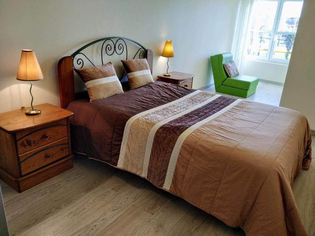 アヴェイロにあるHome Aveiro Riaのベッドルーム(大型ベッド1台、緑の椅子付)