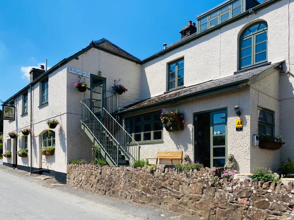 ein weißes Backsteingebäude mit einer Steinmauer in der Unterkunft The Royal Oak Inn in Withypool