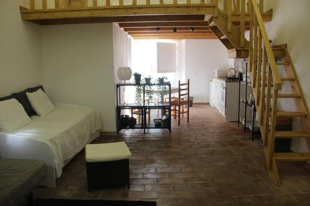 a living room with a bed and a staircase at Casa do Páteo in Olhão