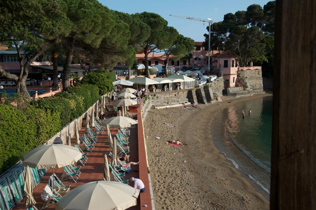 a beach with umbrellas and people sitting on the beach at Hotel Fiascherino in Lerici