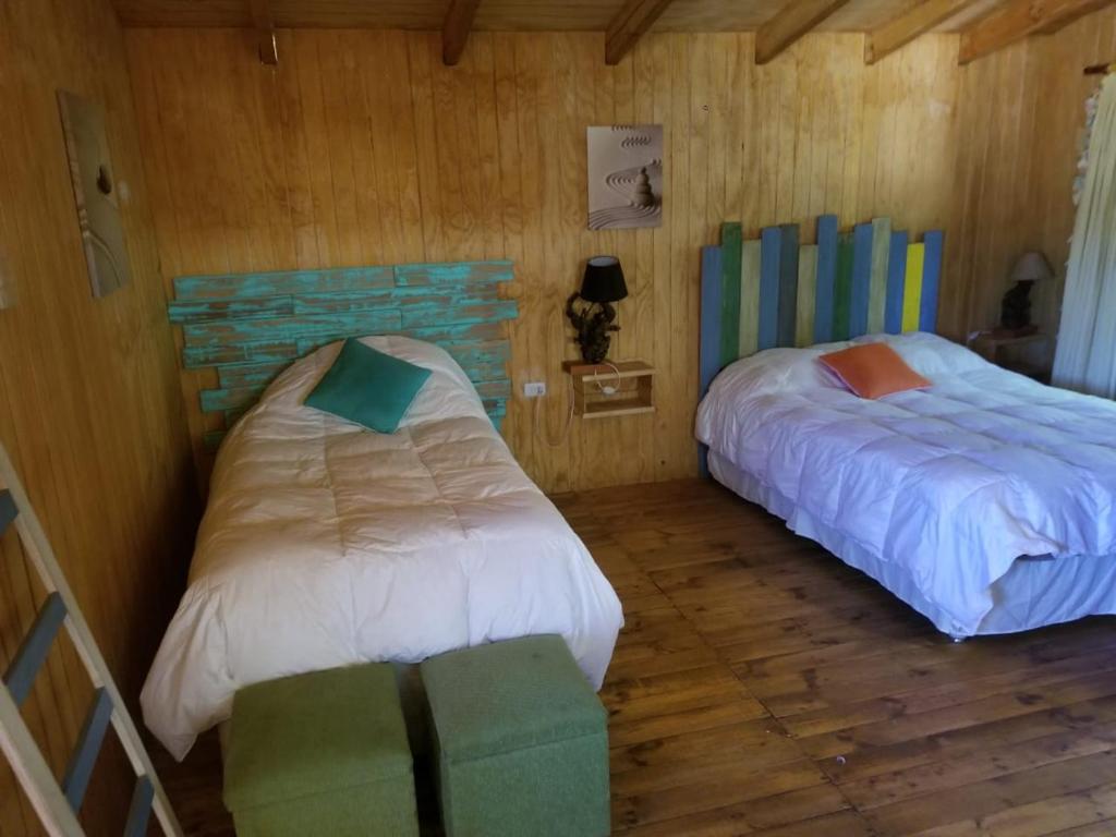 Habitación con 2 camas, paredes de madera y suelo de madera. en Viña Don Heraldo, en De Cauquenes