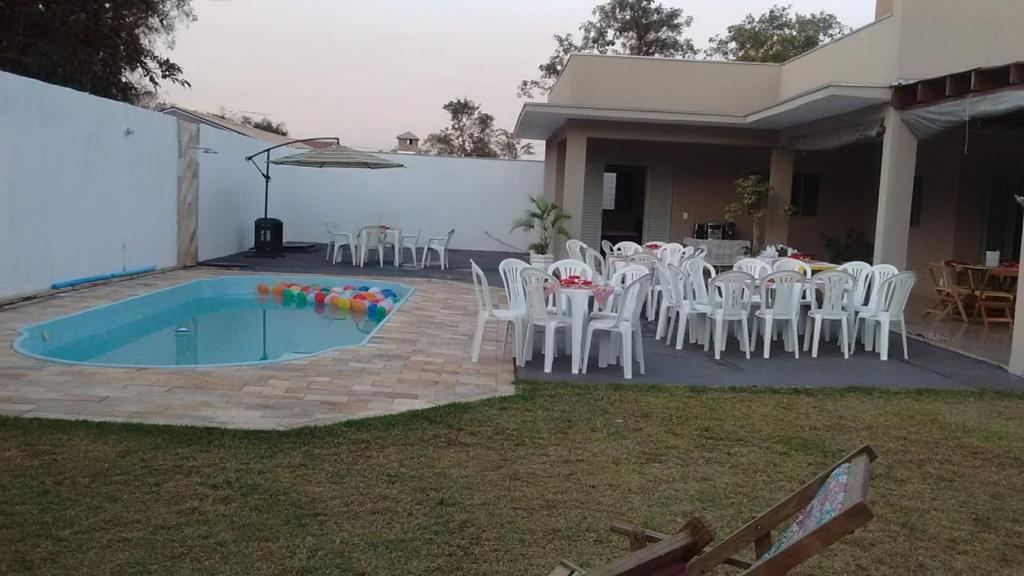 un patio con mesa, sillas y piscina en Casa - Chácara Bella Arraes, en Bauru