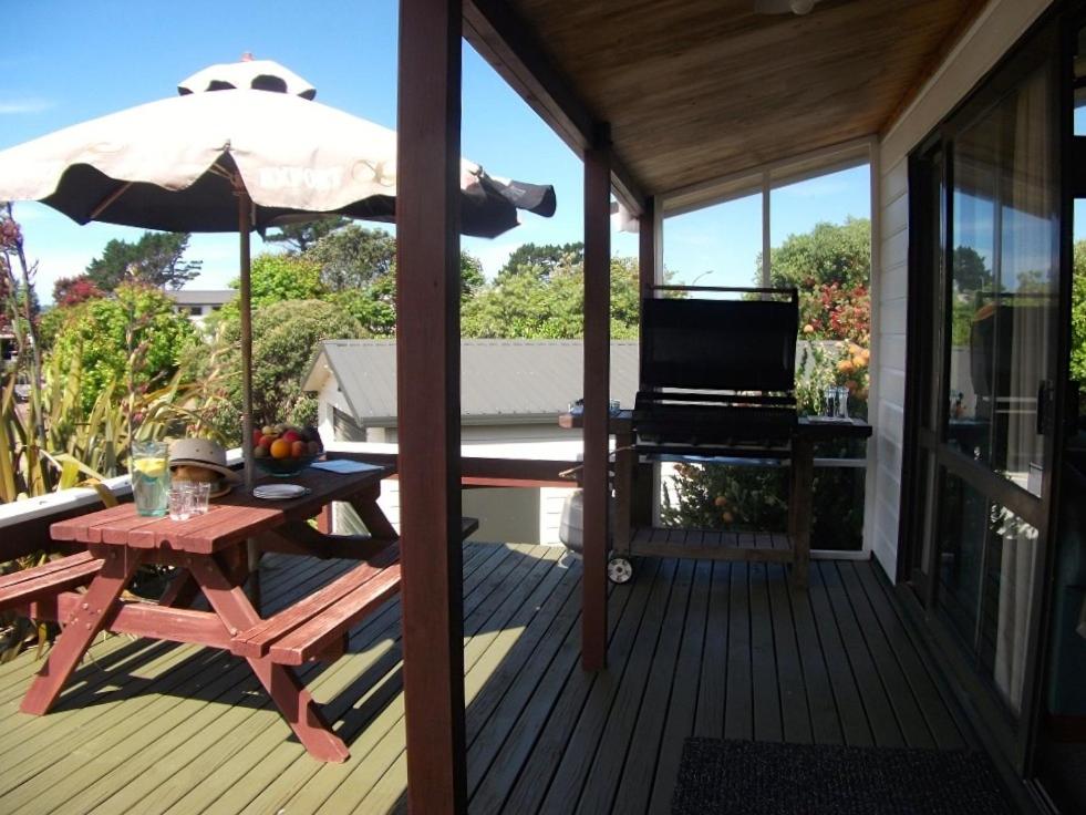 a deck with a picnic table and an umbrella at Relax at Pauanui - Pauanui Holiday Home in Pauanui