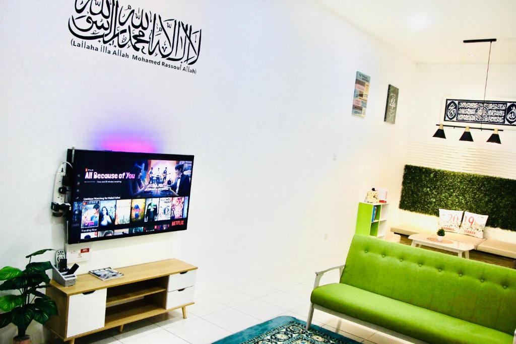a living room with a green couch and a tv at Bismillah Homestay Muslem NETFLIX UNIFI HIGH SPEED in Kamunting