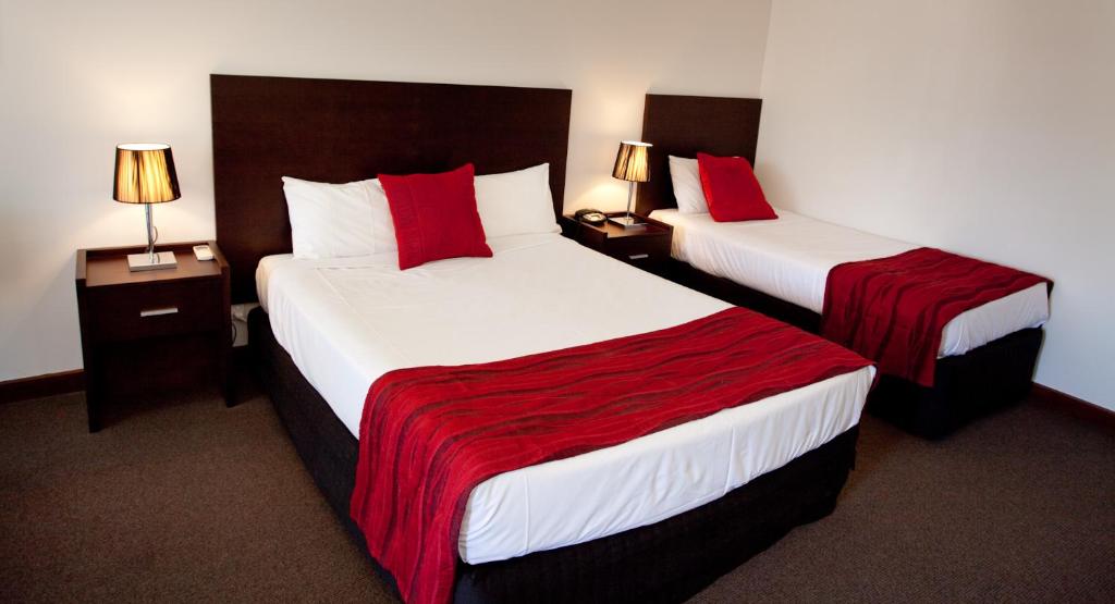 duas camas num quarto de hotel com almofadas vermelhas em Mercure Port of Echuca em Echuca