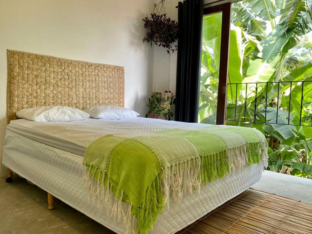 um quarto com uma cama com um cobertor verde em Casa Praiana no Guarujá