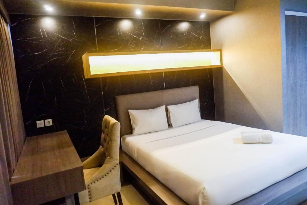 a bed in a room with a table and a bed sidx sidx sidx at Modern Spacious Studio Room Apartment at Taman Melati Surabaya By Travelio in Surabaya