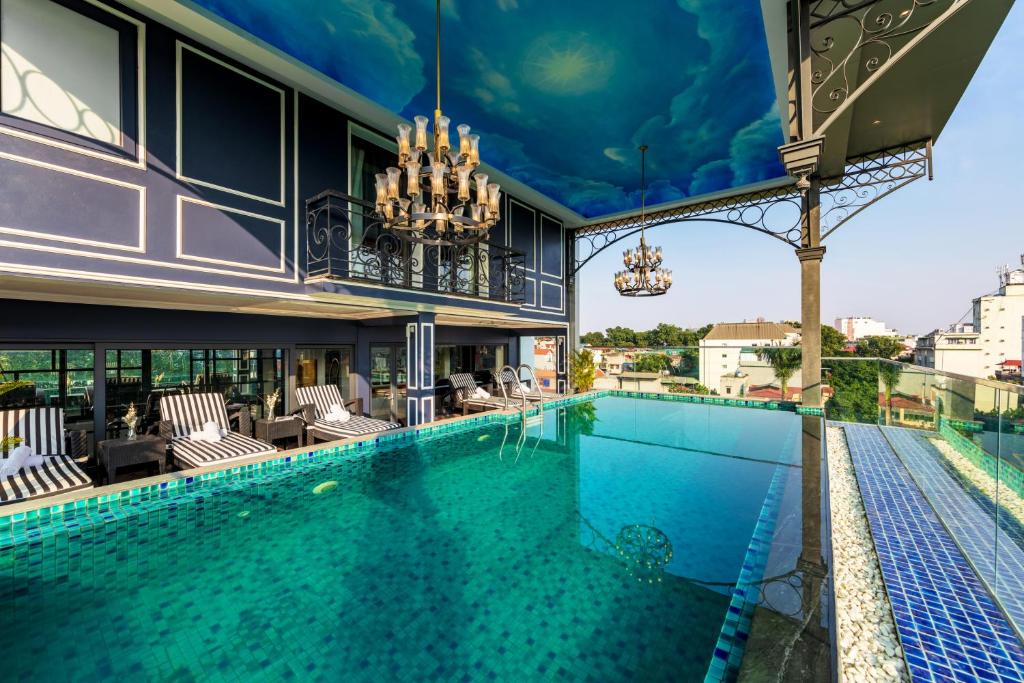 a large swimming pool with chairs and a building at Aira Boutique Hanoi Hotel & Spa in Hanoi