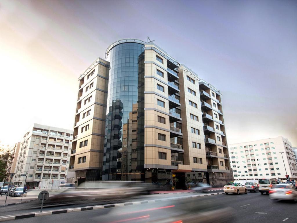 un edificio alto con coches delante en Xclusive Maples Hotel Apartment, en Dubái