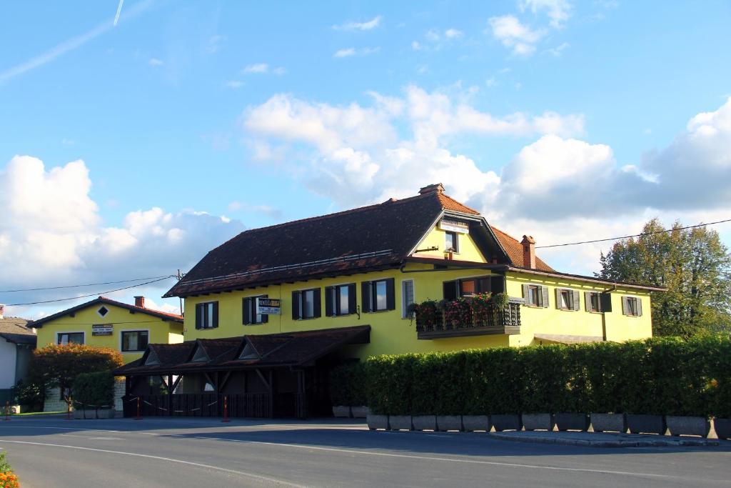 a yellow house with a balcony on a street at Prenočišča Kralj in Komenda