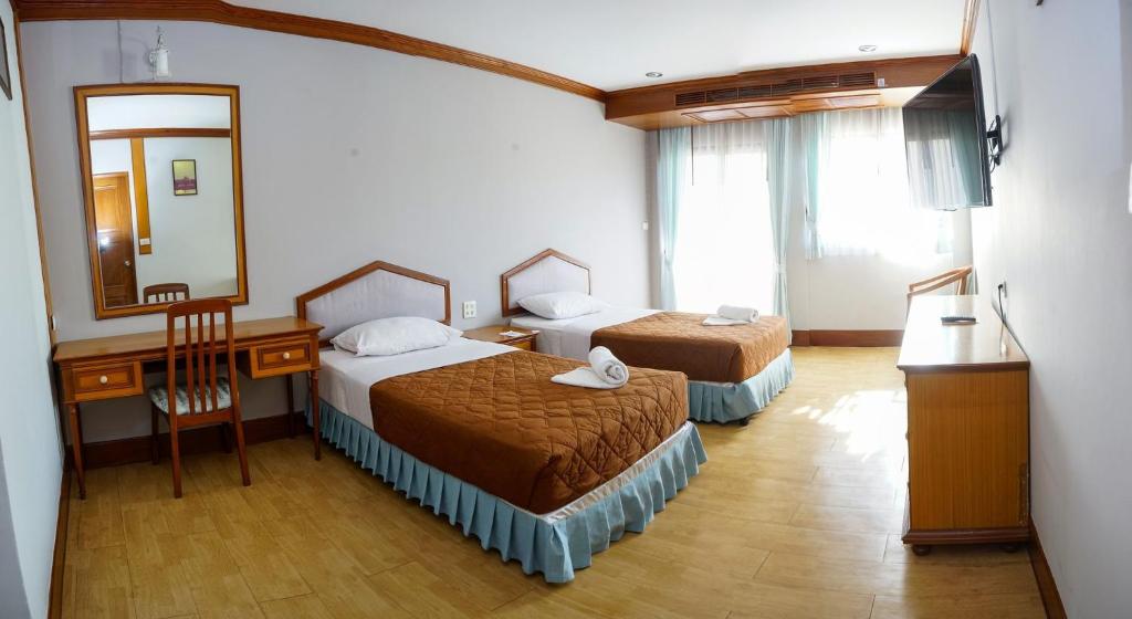 una camera d'albergo con due letti e uno specchio di อุทยานบ้านเชียงเครือ a Ban Nong Bua Sang