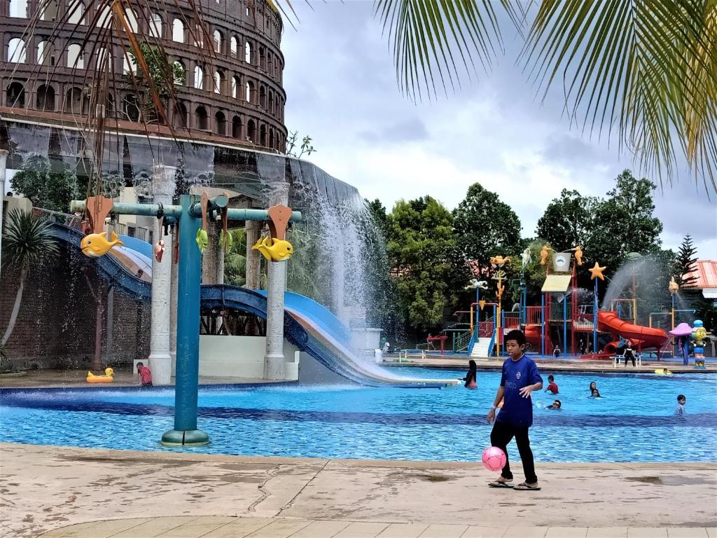 a girl playing with a ball in front of a water park at Melaka BY LG Water Themepark & Resort Melaka By GGM in Melaka