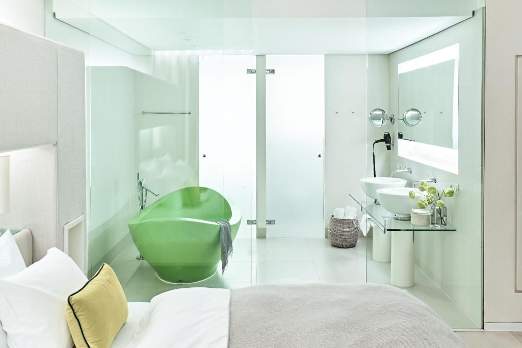 a white bathroom with a green tub and a sink at SIDE, Hamburg, a Member of Design Hotels in Hamburg