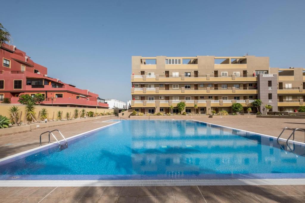 a large swimming pool in front of a building at Apartamento en el Médano in El Médano